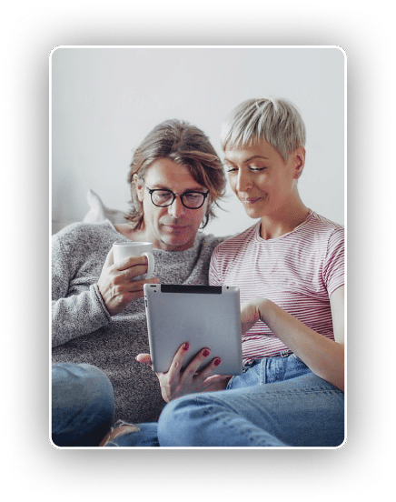 a man and woman enjoying a cup of coffee and reading something together on an ipad