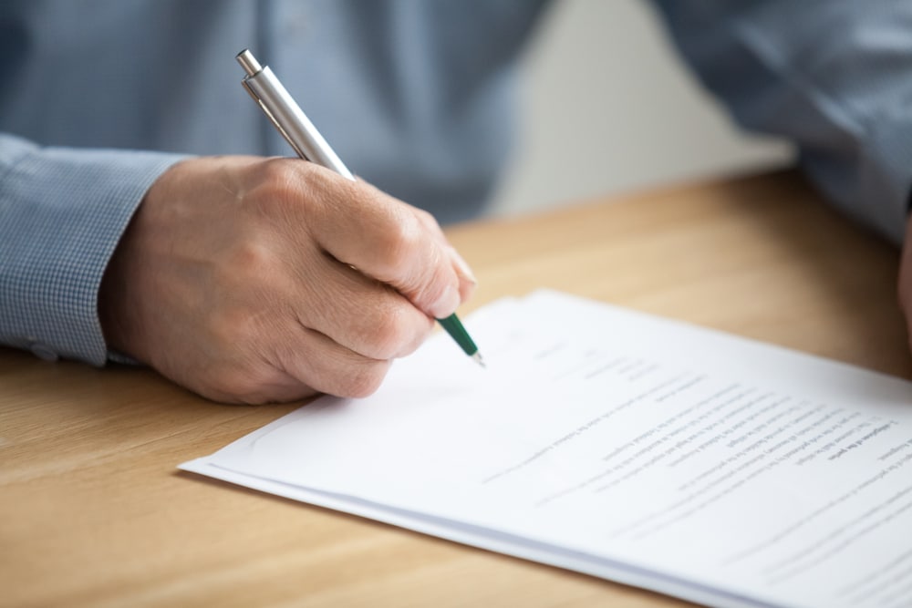 older man signing business documents for cash house buying paperwork