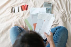 a stressed woman reviewing debt paperwork and trying to manage debts after being made redundant